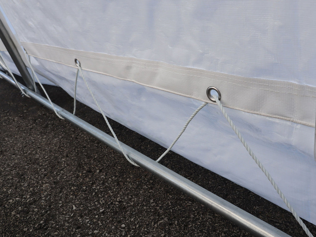 Laçage au bas de la toile d’un abri d’auto, le long du tube horizontal.