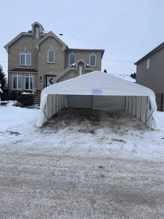 Abri d’auto double installé devant un garage dans une entrée résidentielle en hiver