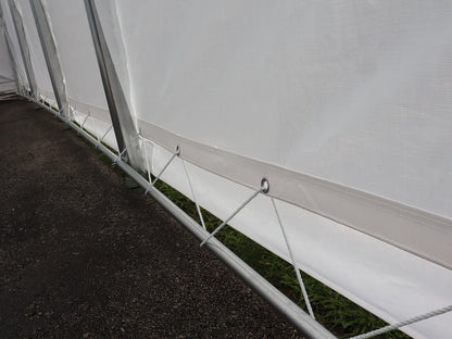 Laçage de la toile aux tubes inférieurs de la structure d’un abri.