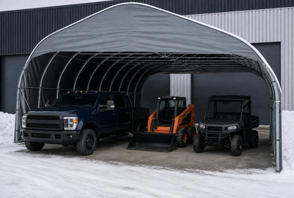 Abri industriel gris à toit arrondi, avec une camionnette et deux véhicules utilitaires.